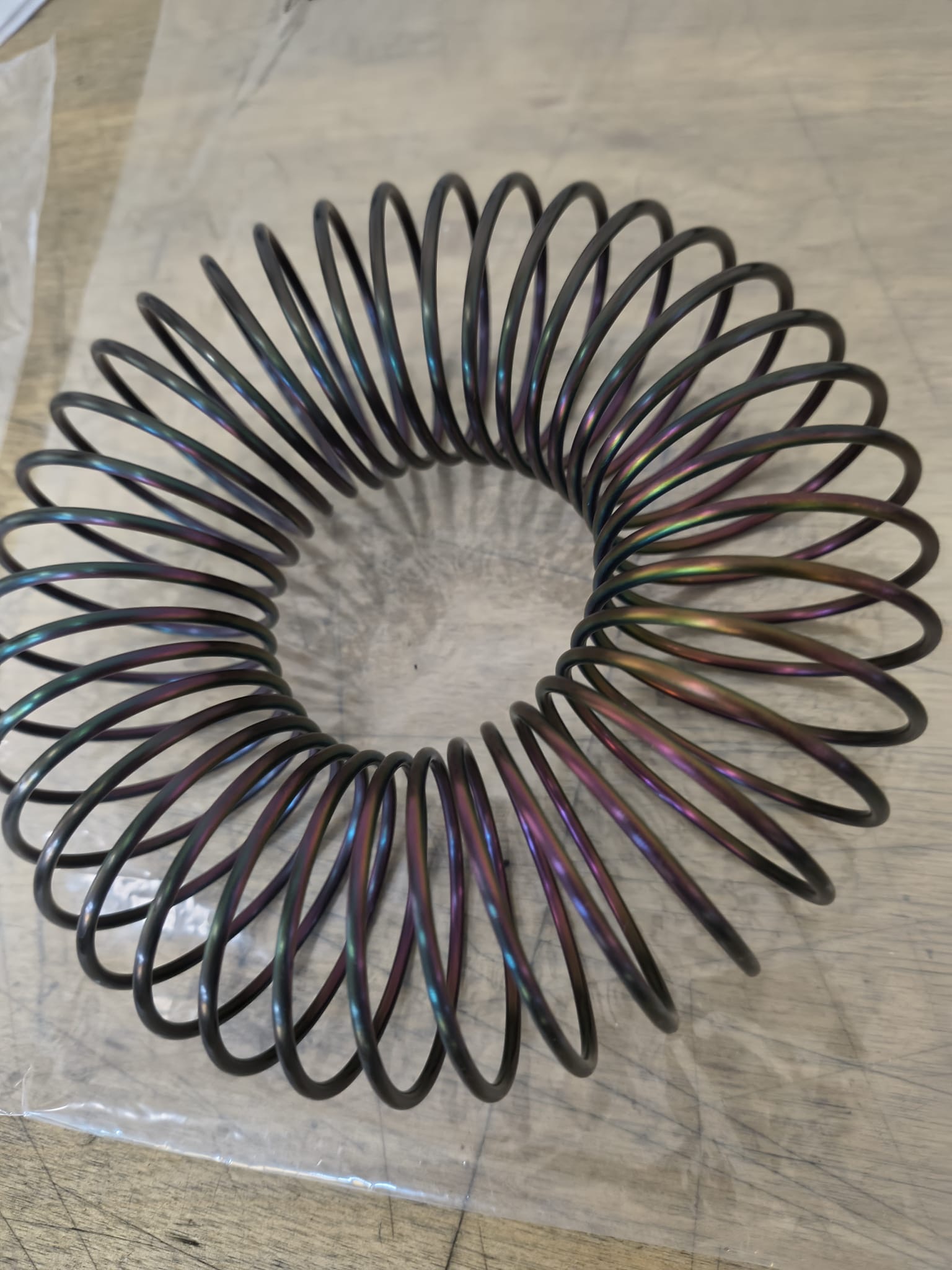 A curved metal coil with iridescent colour across its turns