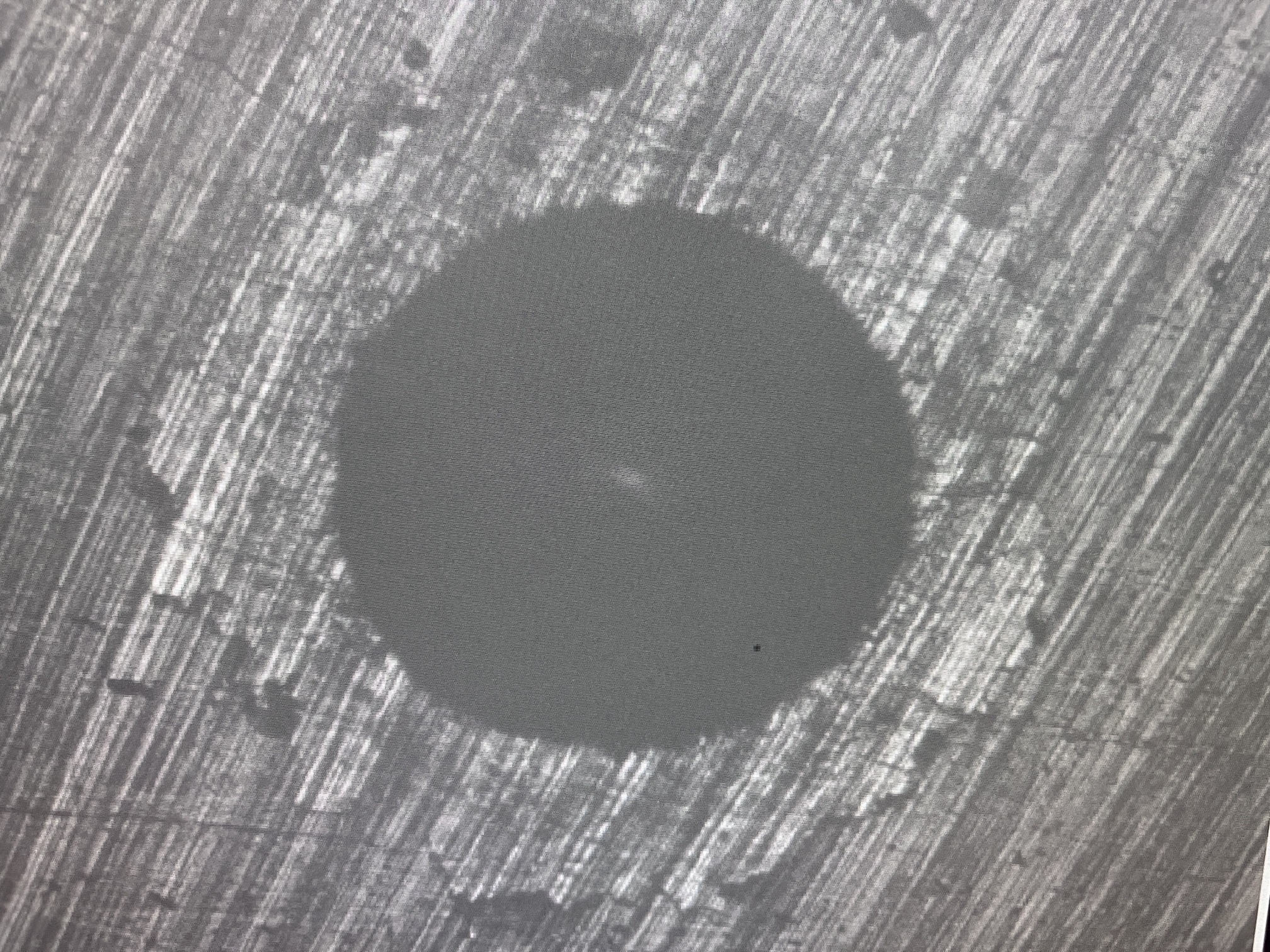 Magnified surface with a circular feature and surrounding diagonal texture